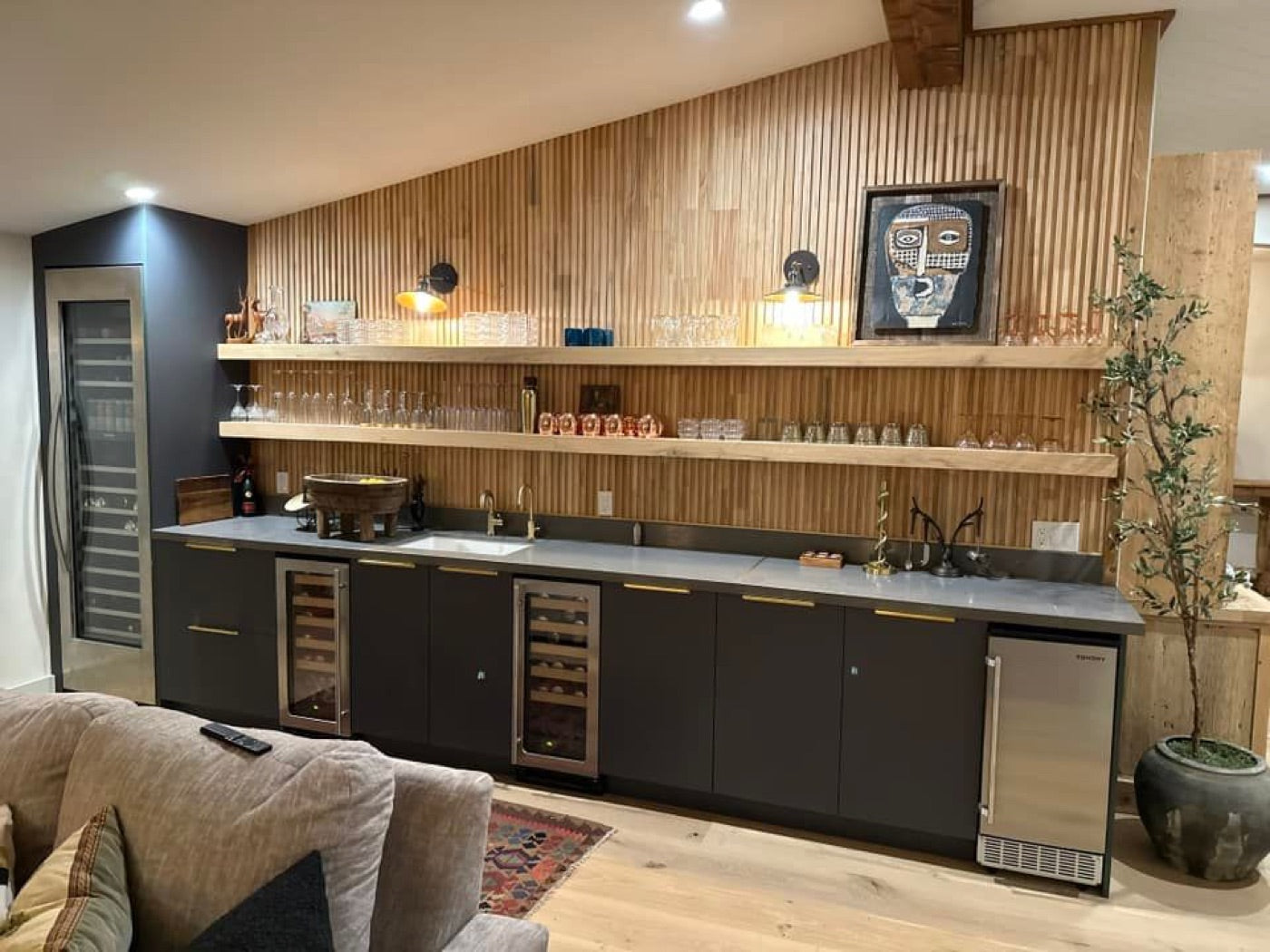 Long floating shelves over a home bar with a slat-wood wall